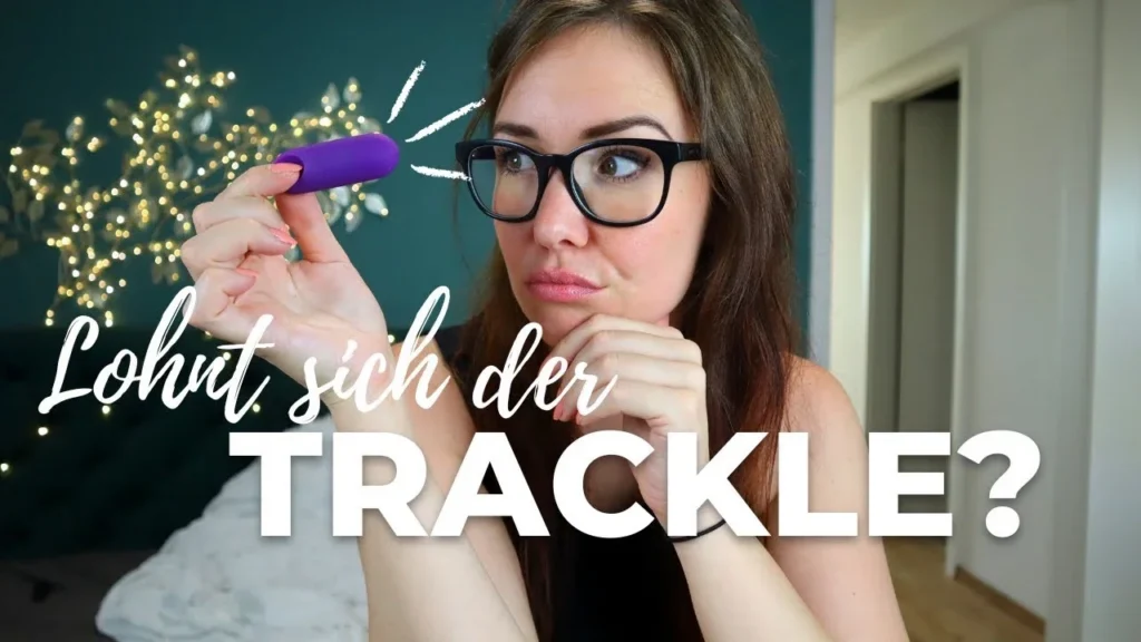Video-Vorschaubild mit der Frage „Lohnt sich der trackle?“. Eine Frau mit Brille hält den lila trackle Sensor prüfend in der Hand und schaut ihn an. Das Bild verspricht einen ehrlichen Testbericht und eine Entscheidungshilfe zum Kauf des trackle Zykluscomputers.